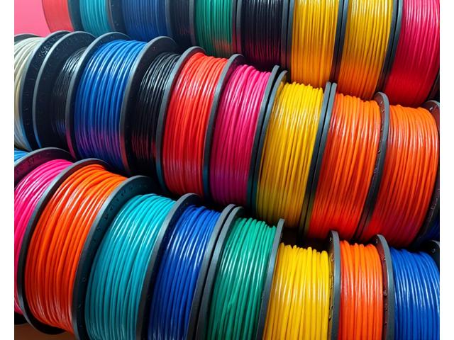 A vibrant collection of diverse 3D printer filament spools in various colors and materials, neatly arranged.